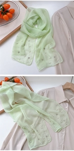 Detail of light green sheer scarf with delicate pearl and rhinestone embellishments