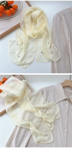 Detail of light yellow sheer scarf featuring decorative pearls and fine sparkling rhinestones