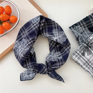 Navy blue plaid cotton scarf with white floral embroidery in a rustic lifestyle setting