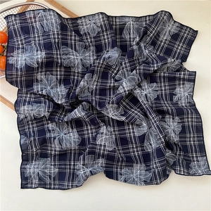 Detail of navy blue cotton scarf featuring white grid and floral line art pattern