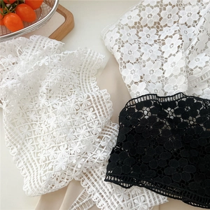 Close-up of intricate floral lace fabric in black and white with hollow crochet details