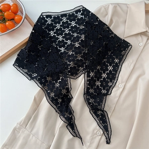 Detail of black crochet lace floral shawl layered over a beige shirt in French style