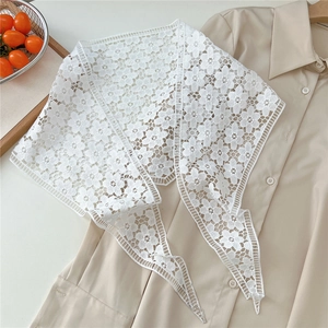 Close-up of white floral lace shawl featuring intricate cutout embroidery on beige shirt