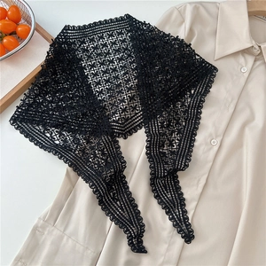 Close-up of black hollow lace crochet triangle scarf with floral patterns on beige shirt