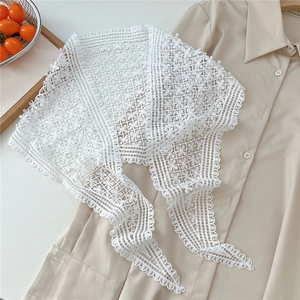 Detailed view of white floral lace shawl styled over a beige button-up cotton shirt