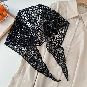 Detail of black floral lace wrap layered over a beige shirt with intricate embroidery
