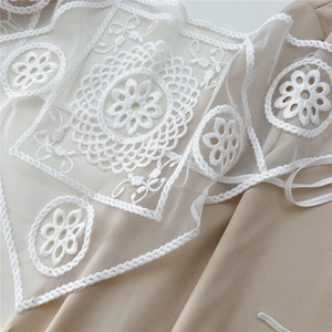 Detailed macro view of white embroidered floral lace fabric with intricate patterns