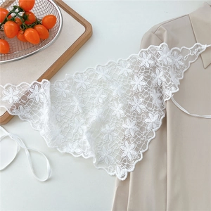 Close-up of white floral embroidery and scalloped lace edge on a pastoral style shawl