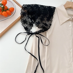 Detail shot of black floral lace headscarf with ties on a minimalist beige fabric