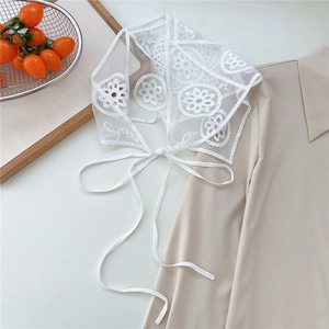Close-up of white floral lace embroidery on sheer mesh fabric with tie straps