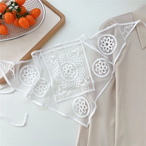 Detailed close-up of white crochet floral lace shawl with delicate mesh and tassel tie