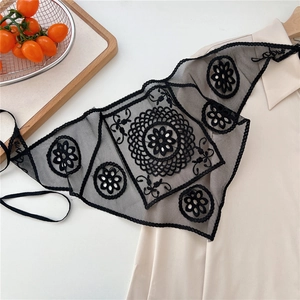 Detailed view of black lace triangular belt with intricate embroidery on beige shirt