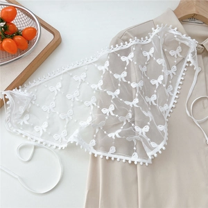 Close-up of white lace waist wrap featuring floral embroidery and decorative pom-pom edges