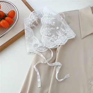 Macro detail of white floral embroidery on a lace shawl with delicate wavy scalloped edges