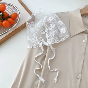 Detailed close-up of white floral lace headscarf with daisy embroidery and delicate ribbons