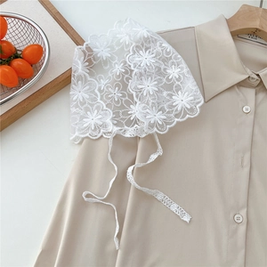 Detail view of white floral lace headscarf with delicate embroidery and ribbons