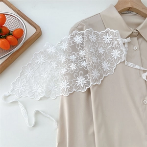 Close-up of white floral embroidery lace headscarf with delicate ribbon and scalloped edges