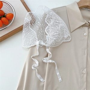 Close-up of vintage white floral lace headscarf with delicate scalloped edges and ribbons