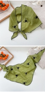 Detail of green triangle scarf featuring floral embroidery and black lace trim edges