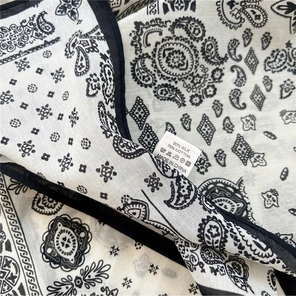 Détail d'un foulard carré en soie et coton montrant la texture et le motif paisley