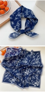 Détail d'un foulard en soie bleu marine avec motifs floraux et bords rayés