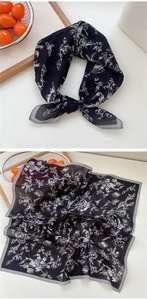 Détail d'un foulard en soie carré avec imprimés d'oiseaux et fleurs noires noué en nœud