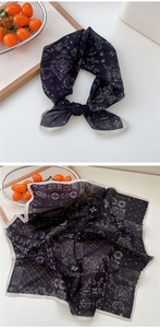 Détail d'un foulard carré en soie avec motifs paisley noir et blanc et bordures roulées