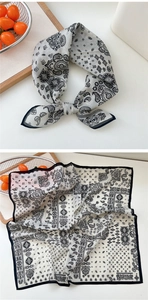 Détail d'un foulard en soie à motif paisley noir et blanc avec nœud et motif à plat