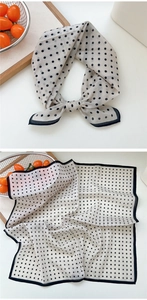 Gros plan d'un foulard carré en soie beige à pois noirs et bordure sur un plateau en bois