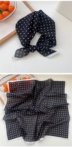 Gros plan sur un foulard carré en soie à pois noirs et blancs avec bordure cousue
