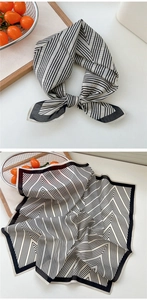 Détail d'un foulard en soie à rayures noires et blanches avec nœud et motif géométrique