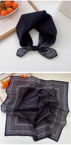 Détail d'un foulard en soie noir avec motif paisley et élégant style noué sur fond blanc
