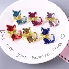 Close-up of colorful sequin cat ear clips with gold bows on a white plate