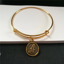 Detailed close-up of a gold adjustable bracelet with an octagonal initial A pendant charm