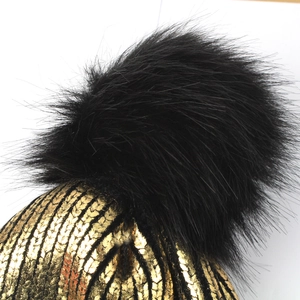 Winter black and gold pinstripe knit beanie with a large decorative faux fur pom-pom