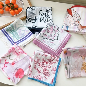 Detail showing a stack of assorted patterned square silk scarves on a clean white background