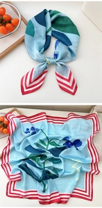 Detailed view of light blue silk scarf with botanical print and red striped borders