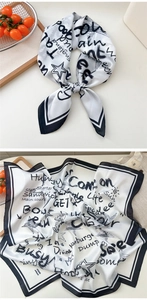 Detail of a white square silk scarf with black graffiti patterns and modern artistic prints