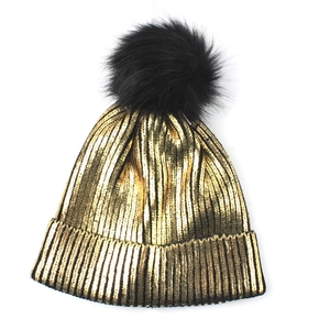 Metallic gold knit beanie with black faux fur pom pom and ribbed texture detailing