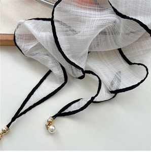 Detailed close-up of white chiffon scarf with elegant pearl and gold bead accents
