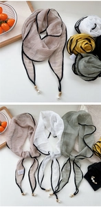 Close-up of lightweight chiffon scarves featuring elegant pearl pendants and black borders