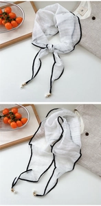 Detail of white diamond scarf with elegant black border, gold charms and pearl drops