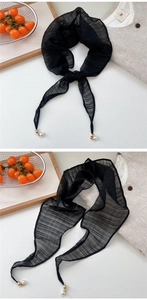Detail of black pleated sheer scarf featuring gold hardware and elegant pearl charms