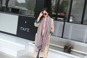 Detail of red and gray plaid oversized scarf with long tassels on a stylish female model