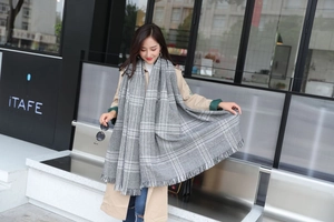 Detail shot of a grey oversized houndstooth scarf with elegant tassel fringes