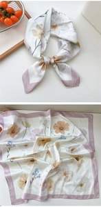 Detailed view of floral silk scarf with cream base and purple borders on wooden tray