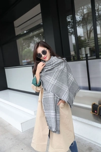 Detail of grey and white houndstooth scarf with elegant fringes and soft cashmere feel