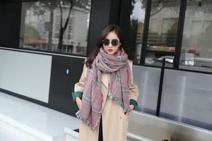 Detailed view of winter thick plaid scarf with classic fringe edges and red grey pattern