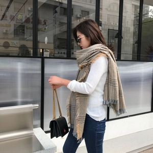 Classic earth-toned plaid scarf with fringe details styled on a model in urban setting