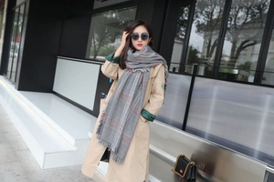 Detail of grey and red checkered scarf with soft tassels and premium winter texture